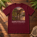 Daspletosaurus t-shirt flat lay – maroon PaleoThreads paleo art tee on a walnut field desk with ferns