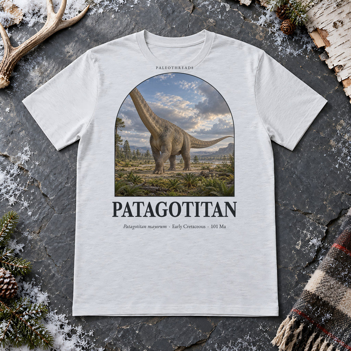 Patagotitan t-shirt flat lay – ash PaleoThreads paleo art tee on frosty slate with an antler