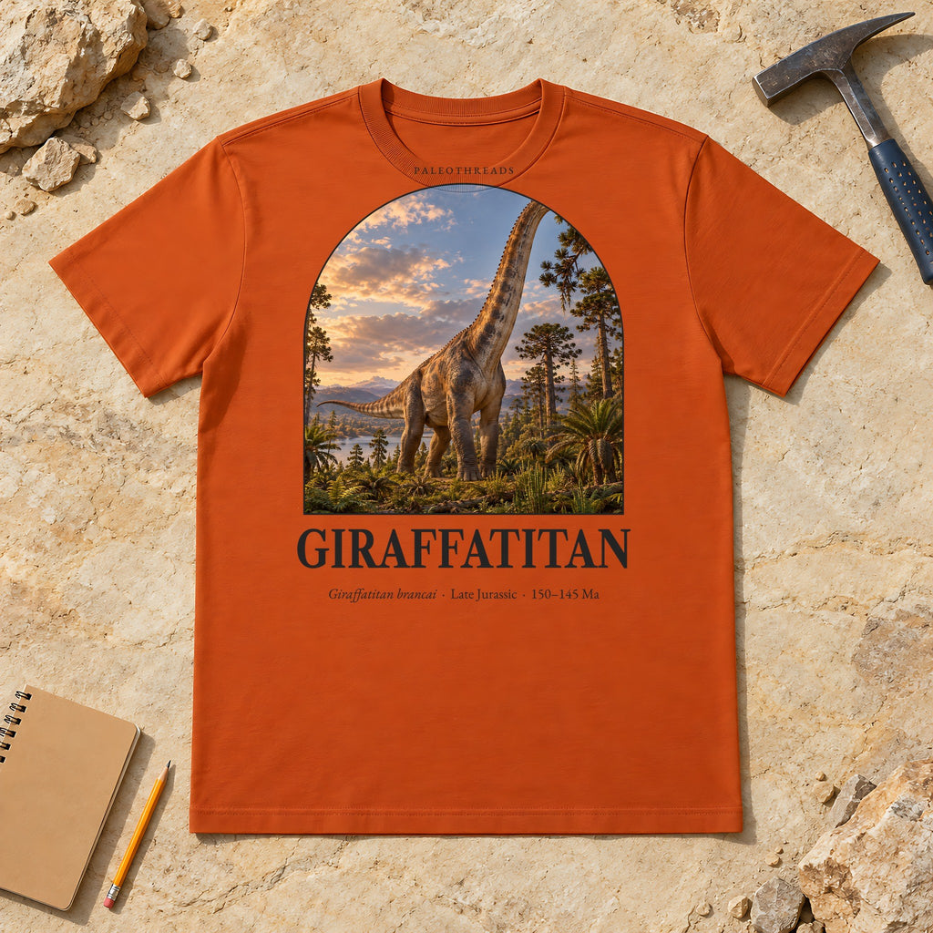 Giraffatitan t-shirt flat lay – autumn PaleoThreads paleo art tee on sandstone with a rock hammer
