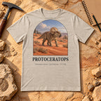 Protoceratops t-shirt flat lay – heather dust PaleoThreads paleo art tee on sandstone with a rock hammer