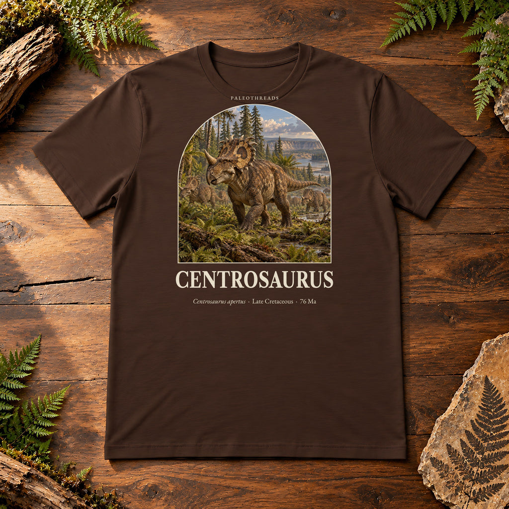 Centrosaurus t-shirt flat lay – brown PaleoThreads paleo art tee on a walnut field desk with ferns