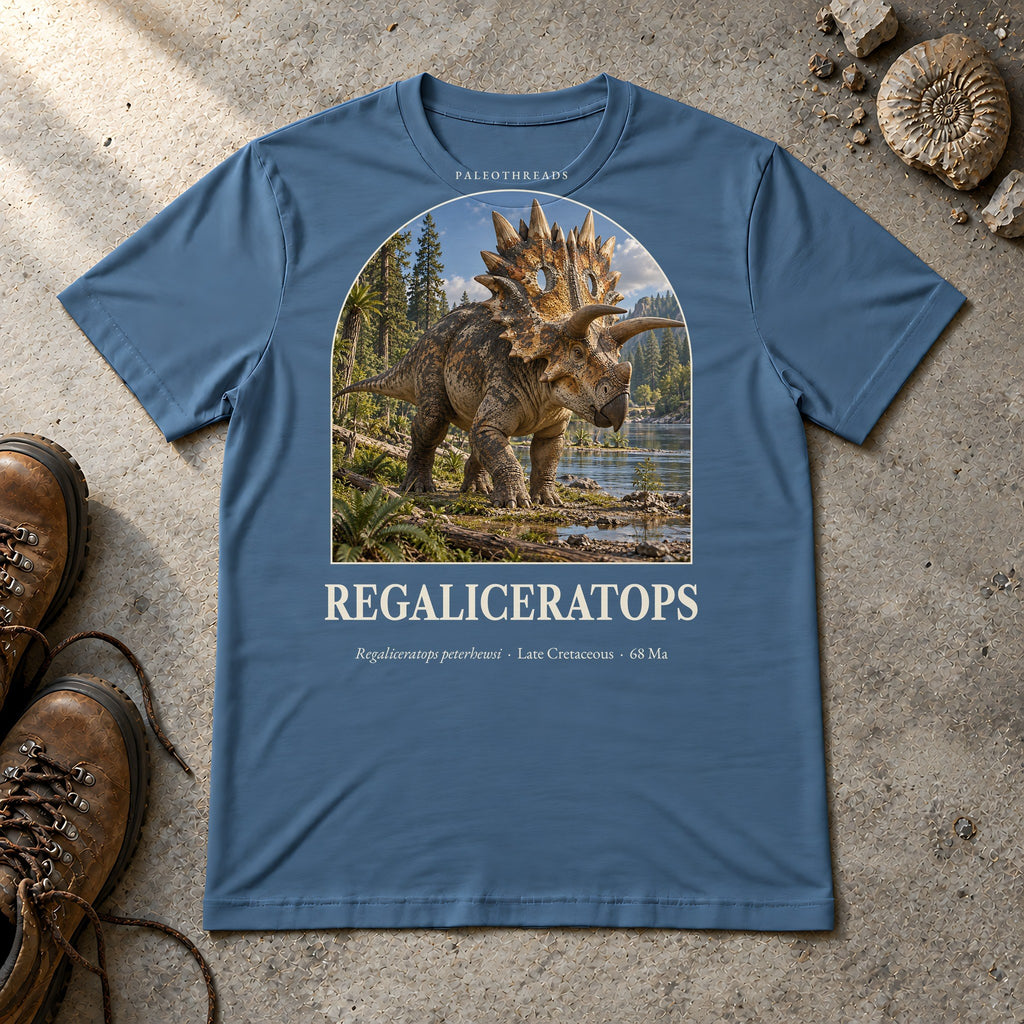 Regaliceratops t-shirt flat lay – steel blue PaleoThreads paleo art tee with hiking boots and an ammonite