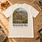 Maiasaura t-shirt flat lay – natural PaleoThreads paleo art tee on a fossil prep bench with amber