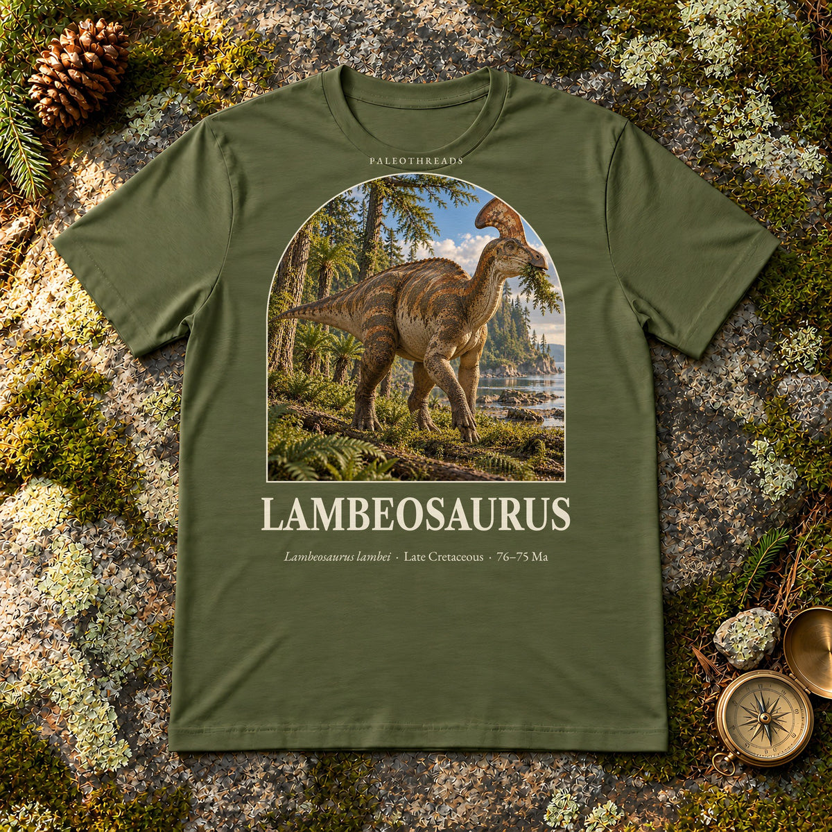 Lambeosaurus t-shirt flat lay – military green PaleoThreads paleo art tee on mossy rock with a brass compass