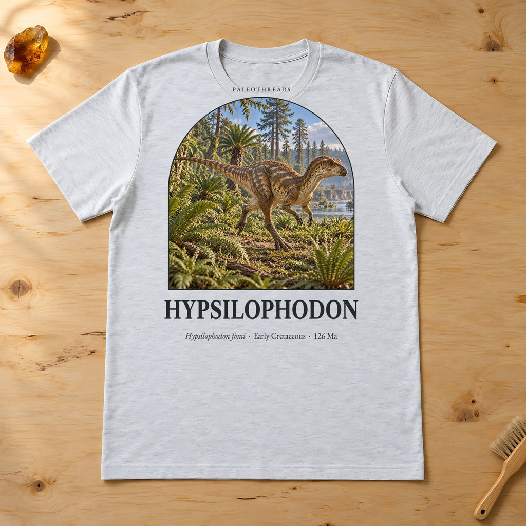 Hypsilophodon t-shirt flat lay – ash PaleoThreads paleo art tee on a fossil prep bench with amber