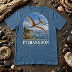 Pteranodon t-shirt flat lay – steel blue PaleoThreads paleo art tee on a fossil beach with driftwood