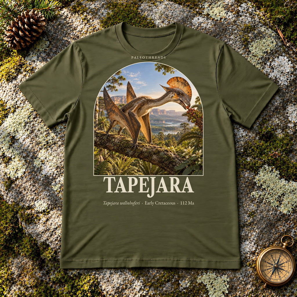 Tapejara t-shirt flat lay – olive PaleoThreads paleo art tee on mossy rock with a brass compass