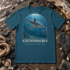Ichthyosaurus t-shirt flat lay – heather deep teal PaleoThreads paleo art tee on a fossil beach with driftwood