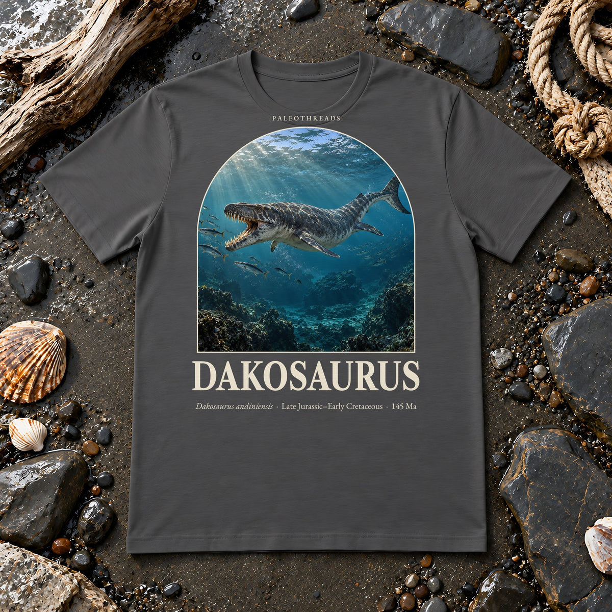 Dakosaurus t-shirt flat lay – asphalt PaleoThreads paleo art tee on a fossil beach with driftwood