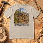 Desmatosuchus t-shirt flat lay – heather dust PaleoThreads paleo art tee on sandstone with a rock hammer