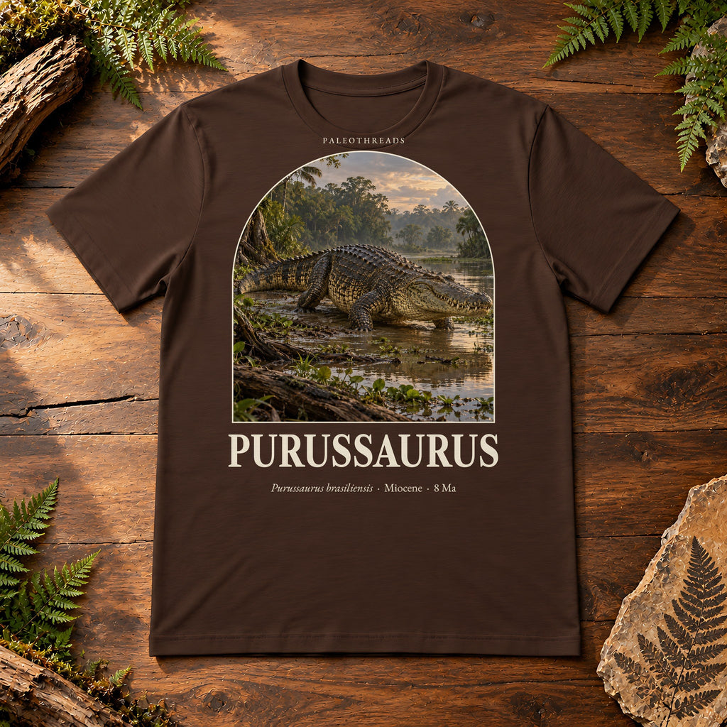 Purussaurus t-shirt flat lay – brown PaleoThreads paleo art tee on a walnut field desk with ferns