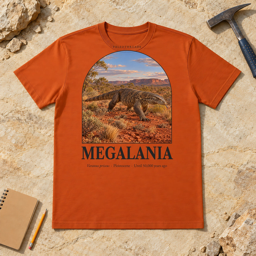 Megalania t-shirt flat lay – autumn PaleoThreads paleo art tee on sandstone with a rock hammer