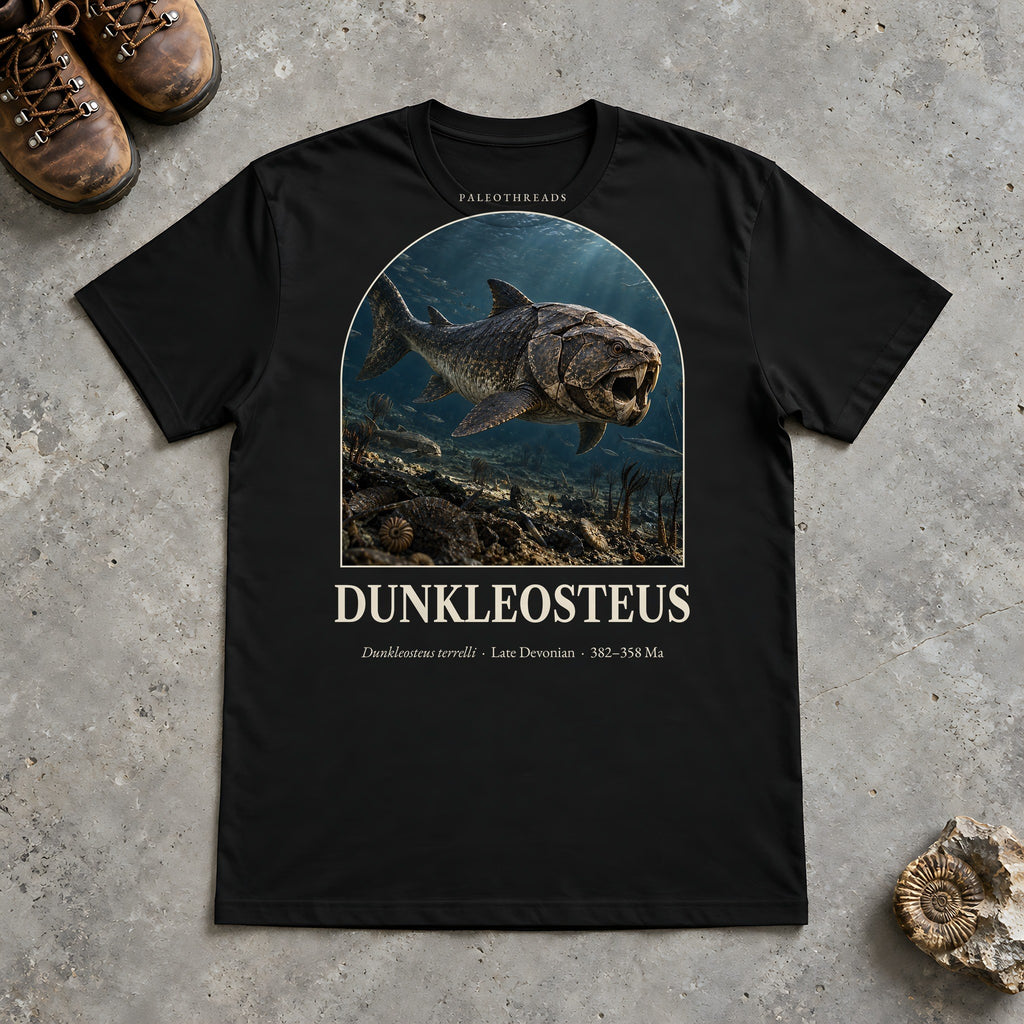 Dunkleosteus t-shirt flat lay – black PaleoThreads paleo art tee with hiking boots and an ammonite