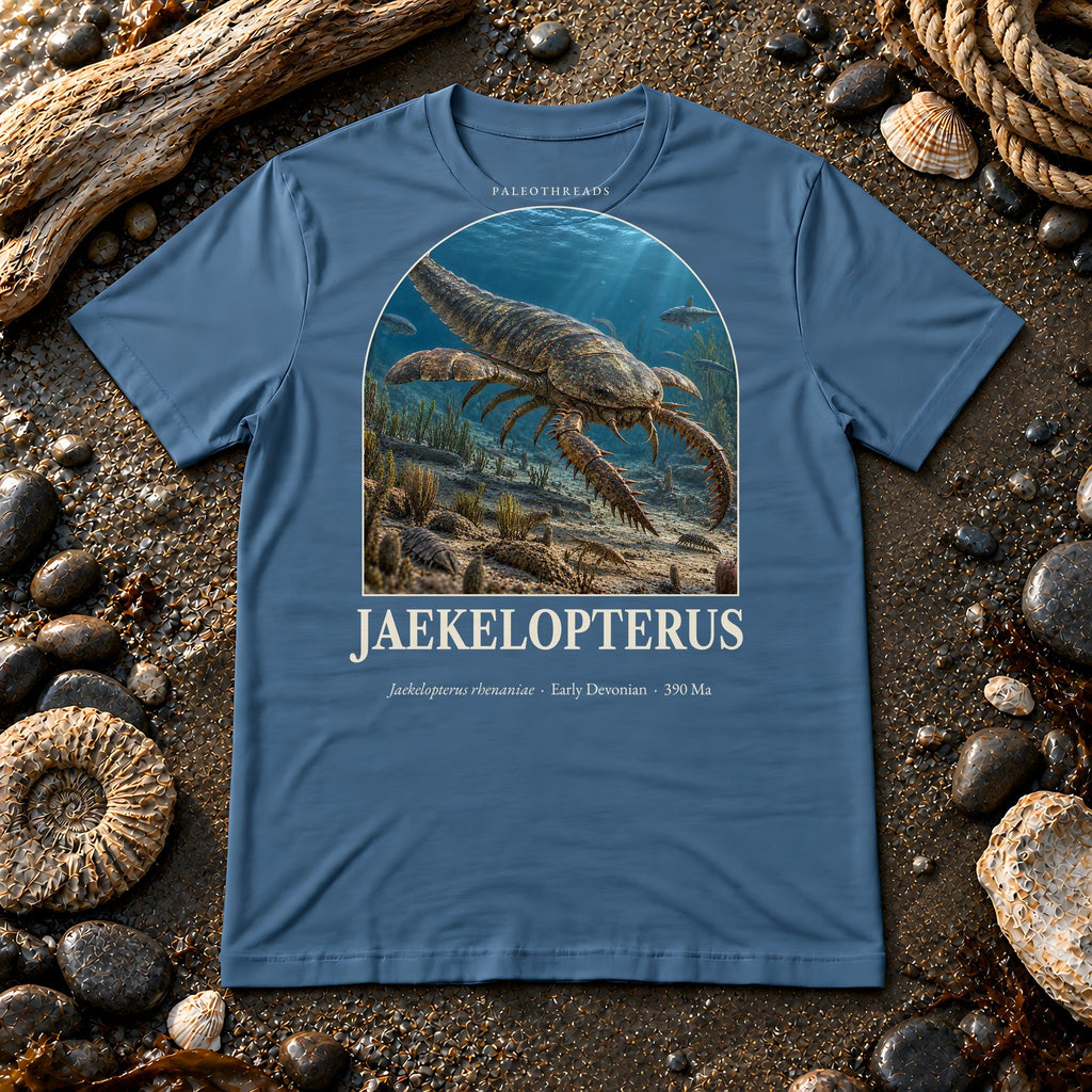 Jaekelopterus t-shirt flat lay – steel blue PaleoThreads paleo art tee on a fossil beach with driftwood