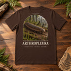 Arthropleura t-shirt flat lay – brown PaleoThreads paleo art tee on a walnut field desk with ferns