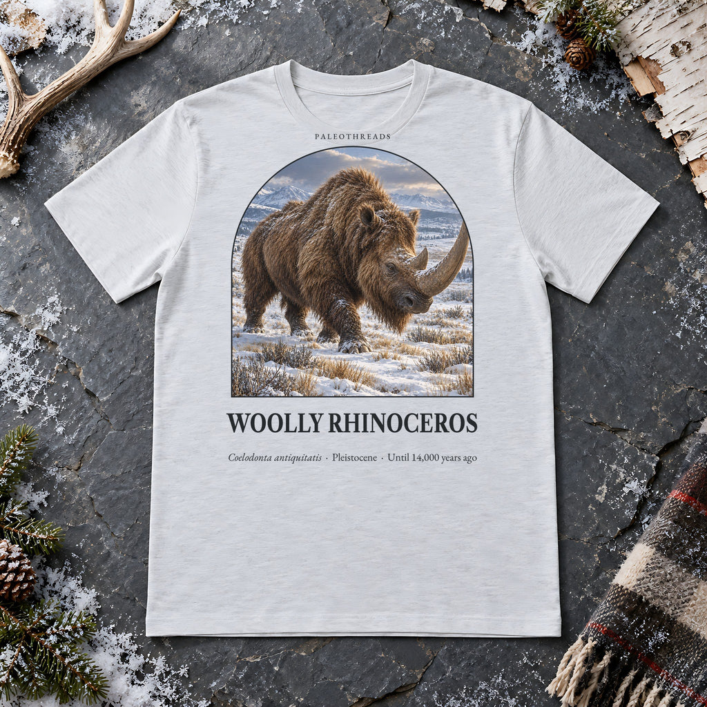 Woolly Rhinoceros t-shirt flat lay – ash PaleoThreads paleo art tee on frosty slate with an antler